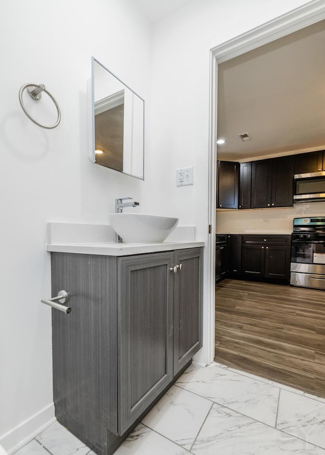 bathroom featuring marble finish floor, baseboards, visible vents, and vanity