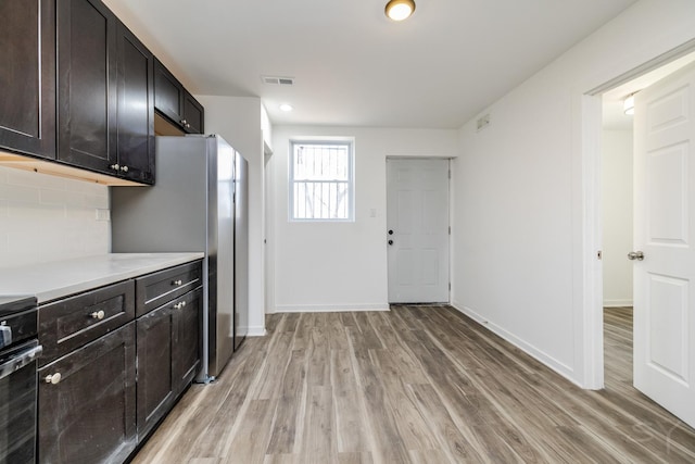 kitchen featuring visible vents, light countertops, light wood-style flooring, and backsplash