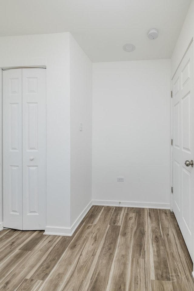 unfurnished bedroom with baseboards, wood finished floors, and a closet