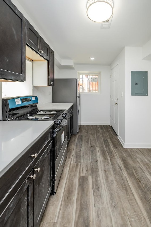 kitchen with light countertops, electric panel, baseboards, wood finished floors, and stainless steel appliances