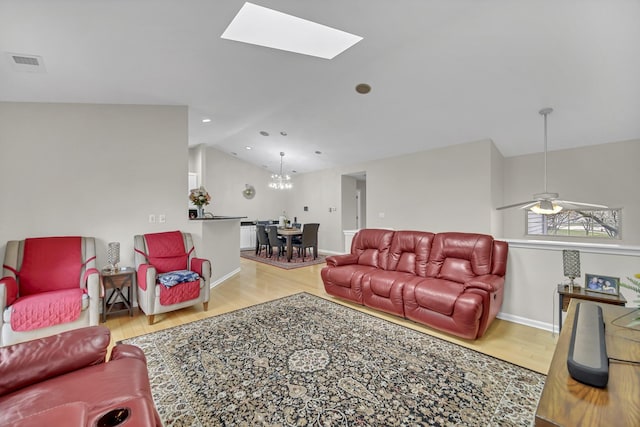 2470 Palazzo Ct, Buffalo Grove, IL 60089 - living area with vaulted ceiling with skylight, visible vents, wood finished floors, baseboards, and ceiling fan with notable chandelier
