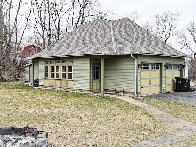 view of front facade featuring a front yard, an attached garage, and a shingled roof