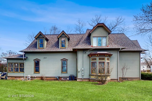 back of property with a yard and roof with shingles