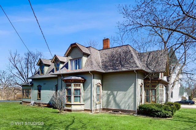 rear view of property featuring a yard, a chimney, and a shingled roof