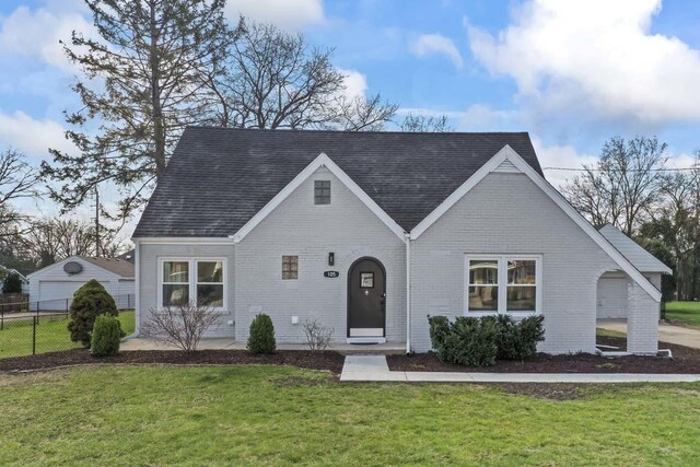 tudor house with fence, a front lawn, and brick siding
