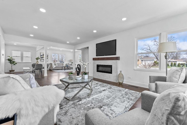 living room with a glass covered fireplace, recessed lighting, plenty of natural light, and baseboards