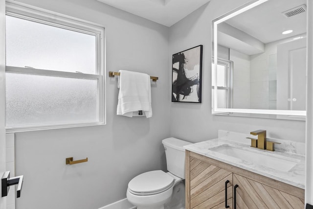 bathroom featuring toilet, vanity, baseboards, and visible vents