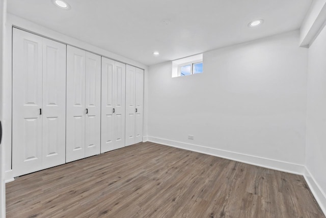 unfurnished bedroom with a closet, baseboards, recessed lighting, and wood finished floors