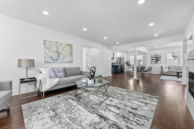 living room with dark wood-type flooring, baseboards, a glass covered fireplace, and recessed lighting