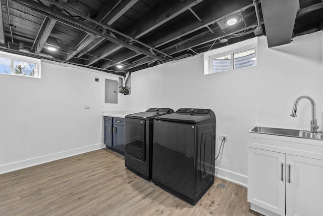 clothes washing area with washing machine and clothes dryer, a sink, light wood finished floors, baseboards, and cabinet space
