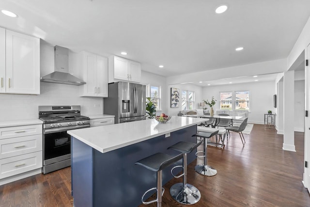 kitchen featuring a kitchen breakfast bar, recessed lighting, light countertops, wall chimney exhaust hood, and appliances with stainless steel finishes