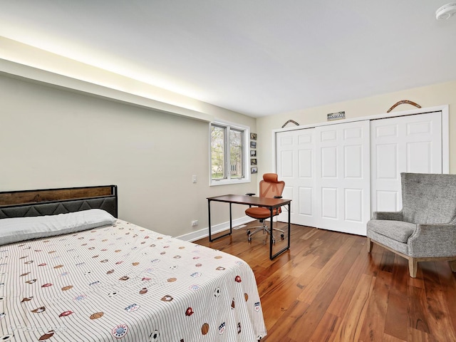 bedroom with baseboards, wood finished floors, and a closet