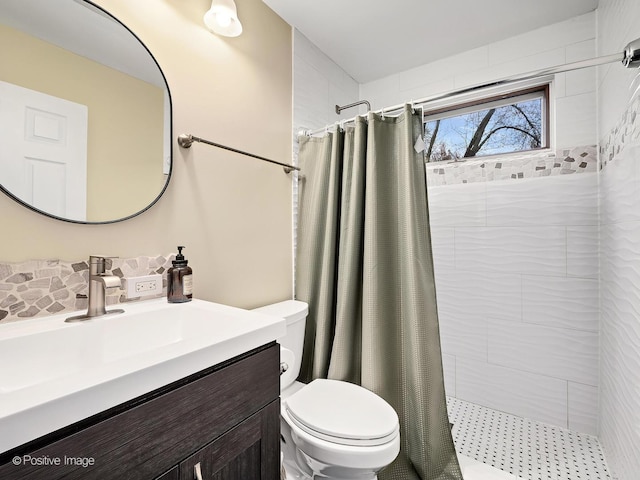 bathroom with a tile shower, vanity, and toilet