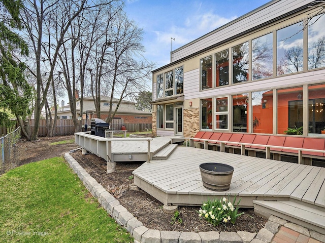 rear view of house featuring a wooden deck, brick siding, and a fenced backyard