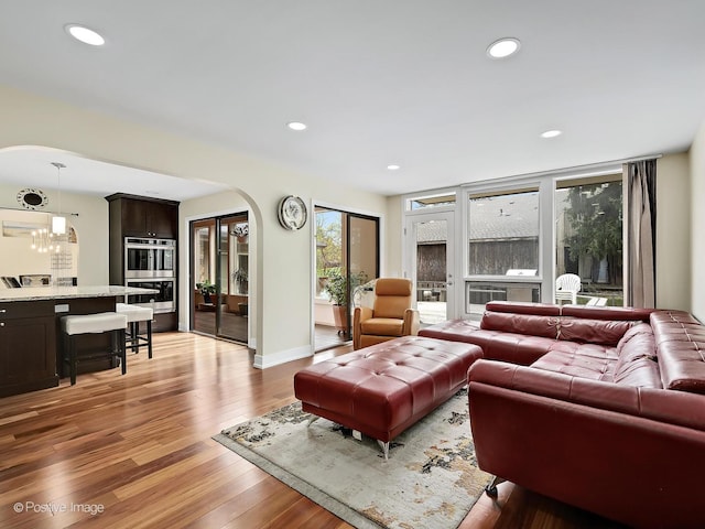 living area featuring arched walkways, light wood finished floors, baseboards, and recessed lighting