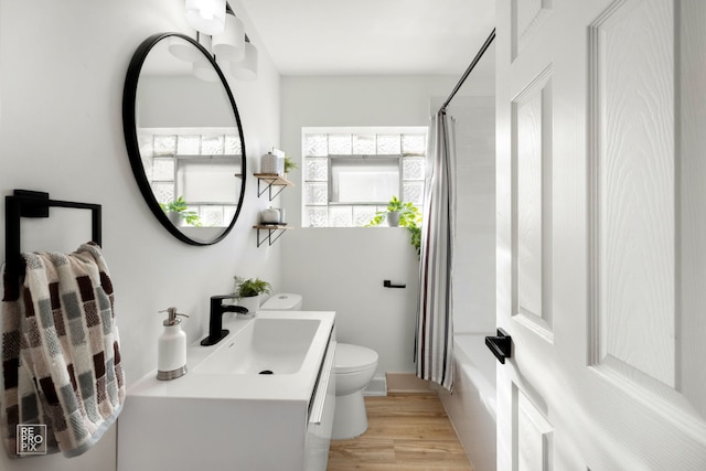 bathroom with shower / bathtub combination with curtain, toilet, vanity, and wood finished floors