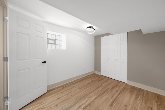 unfurnished bedroom with light wood-style flooring, a closet, and baseboards
