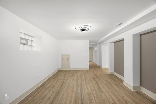spare room with baseboards, light wood-style floors, and visible vents