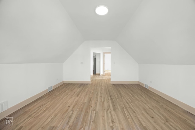 bonus room featuring baseboards, light wood-style flooring, visible vents, and vaulted ceiling