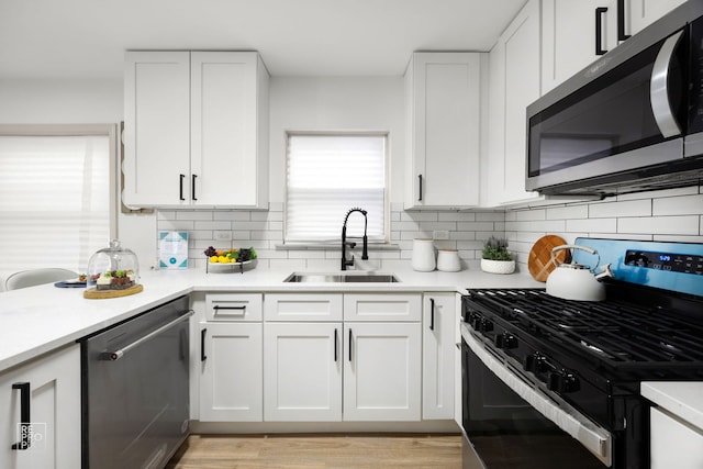 kitchen featuring light countertops, a sink, white cabinetry, appliances with stainless steel finishes, and decorative backsplash