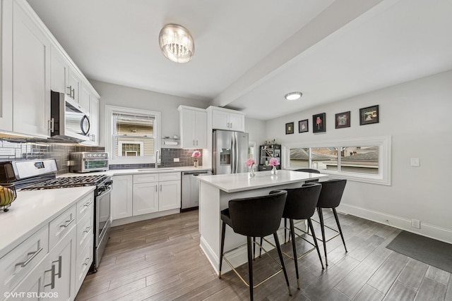 6317 W Roscoe St, Chicago, IL 60634 - kitchen with stainless steel appliances, healthy amount of natural light, a kitchen breakfast bar, and tasteful backsplash