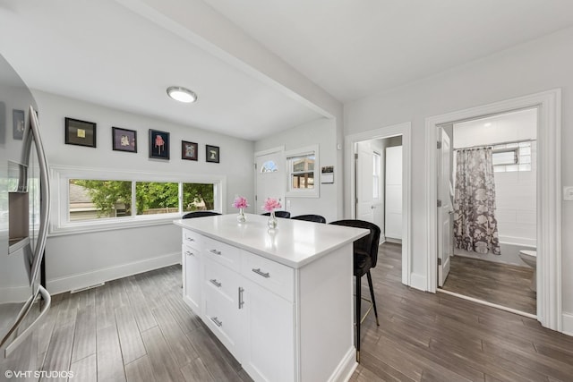 6317 W Roscoe St, Chicago, IL 60634 - kitchen featuring a kitchen bar, freestanding refrigerator, white cabinetry, dark wood-style floors, and a center island