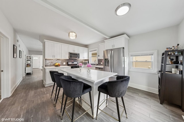 6317 W Roscoe St, Chicago, IL 60634 - kitchen featuring stainless steel appliances, a kitchen bar, and white cabinetry