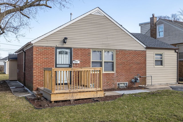 back of house with brick siding and a yard