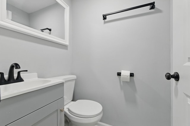 bathroom with toilet, vanity, and baseboards