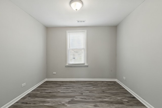 unfurnished room featuring baseboards, visible vents, and dark wood finished floors