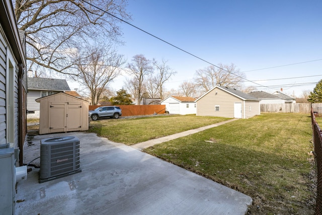 view of yard with fence, central AC, an outdoor structure, and a shed