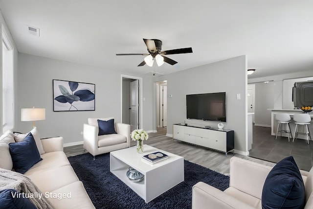 living area featuring baseboards, visible vents, wood finished floors, and a ceiling fan