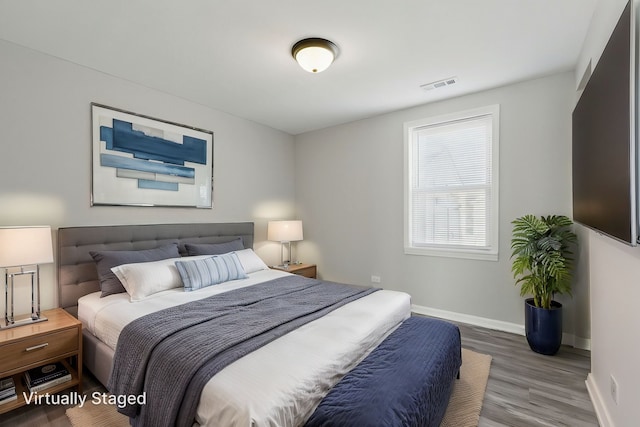 bedroom featuring baseboards, visible vents, and wood finished floors
