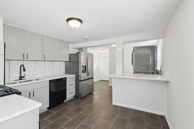 kitchen with light countertops, tasteful backsplash, baseboards, a sink, and black appliances
