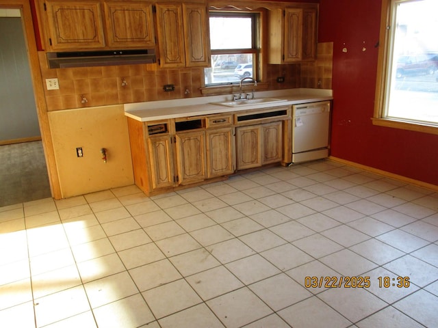 kitchen with white dishwasher, light countertops, a sink, and under cabinet range hood