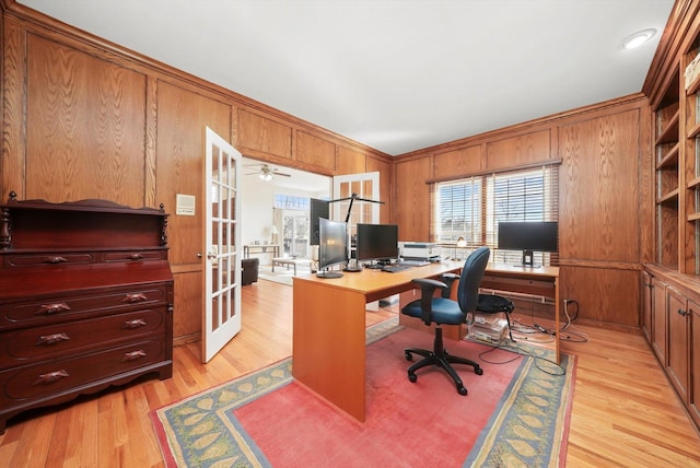 office space featuring wood walls, ornamental molding, ceiling fan, light wood-type flooring, and french doors