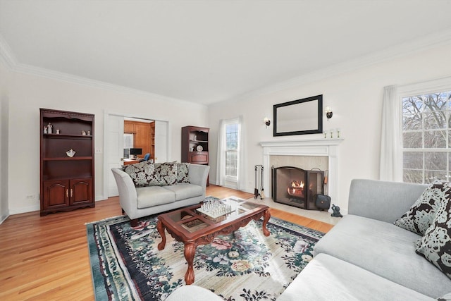 living room featuring ornamental molding, a fireplace with flush hearth, baseboards, and light wood finished floors