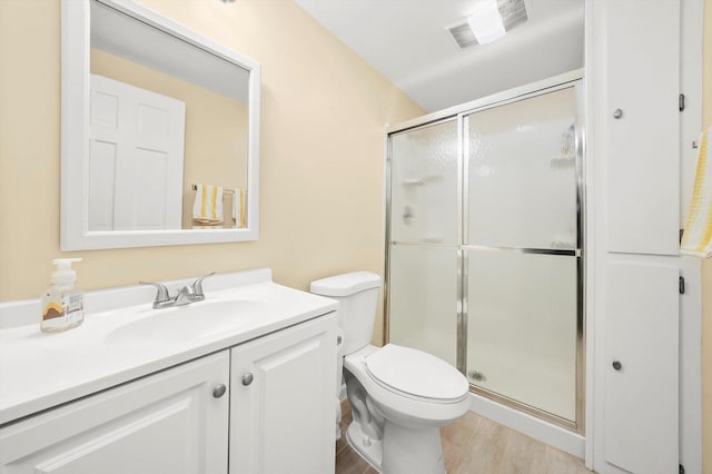 bathroom with visible vents, toilet, wood finished floors, vanity, and a stall shower