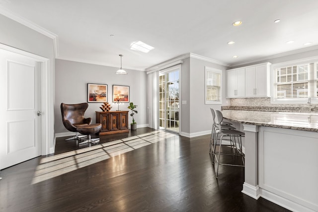 104 W Kennedy Ln, Hinsdale, IL 60521 - kitchen featuring crown molding, healthy amount of natural light, white cabinets, baseboards, and a kitchen breakfast bar