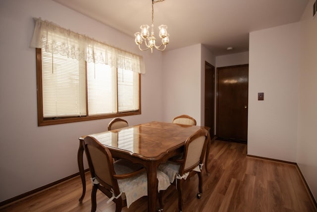dining space featuring visible vents, baseboards, a chandelier, and wood finished floors