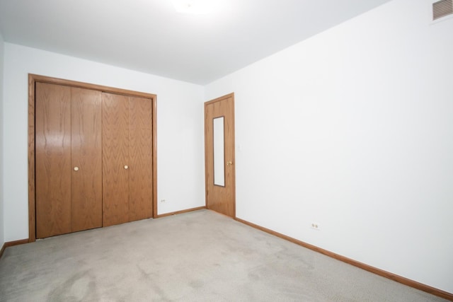 unfurnished bedroom with light carpet, baseboards, a closet, and visible vents