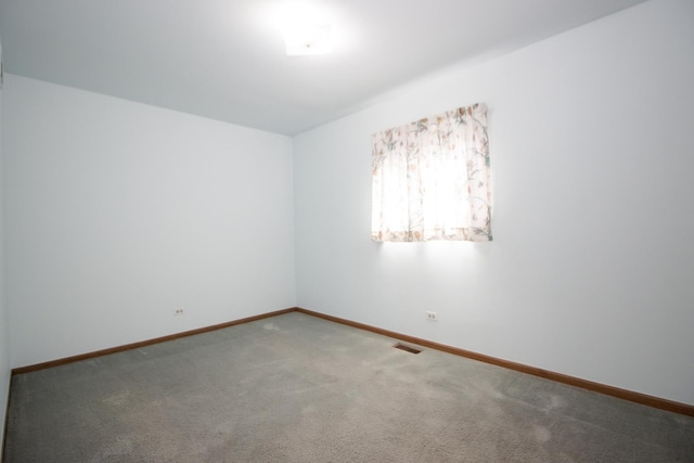 spare room featuring carpet flooring, baseboards, and visible vents