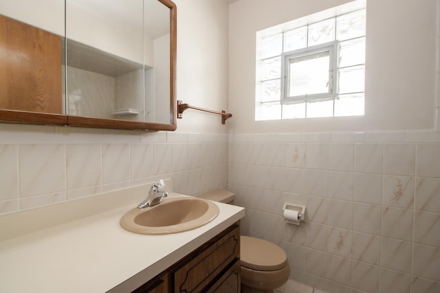bathroom featuring toilet, vanity, and tile walls