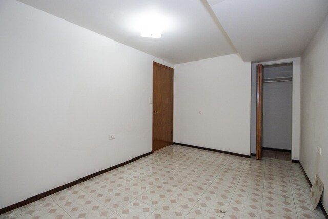 unfurnished bedroom featuring baseboards, a closet, and light floors