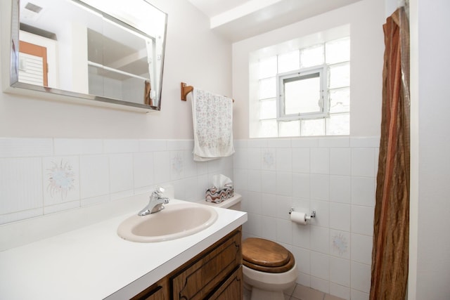 bathroom featuring vanity, tile walls, toilet, curtained shower, and wainscoting