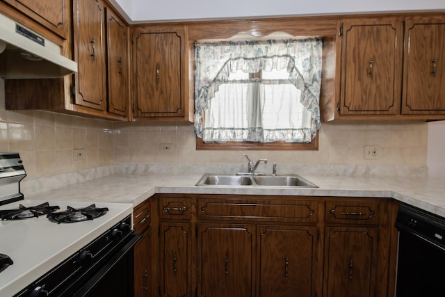 kitchen with gas range oven, under cabinet range hood, decorative backsplash, a sink, and dishwasher