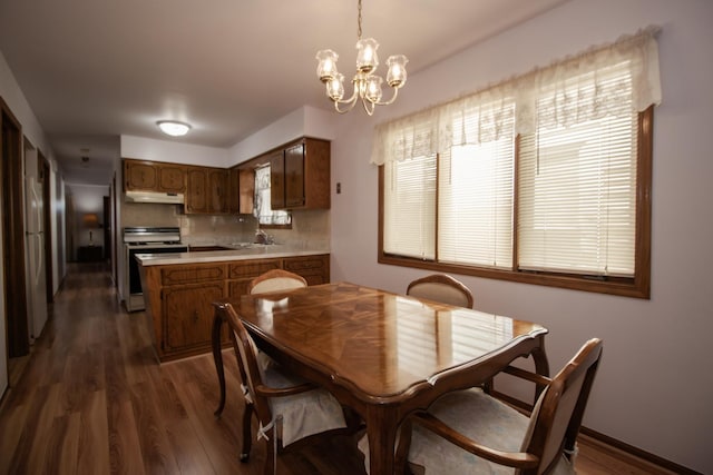 dining room with dark wood-type flooring and an inviting chandelier