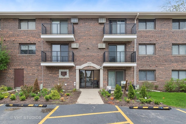 view of building exterior with uncovered parking and a wall mounted air conditioner