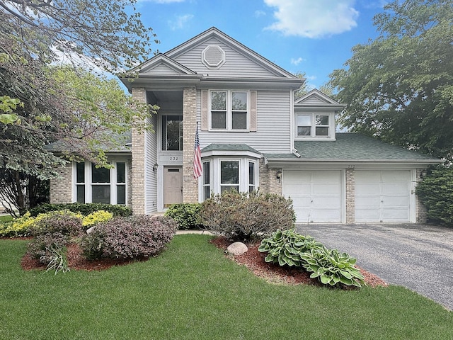 232 Southfield Dr, Vernon Hills, IL 60061 - traditional-style house with asphalt driveway, a front lawn, an attached garage, and brick siding