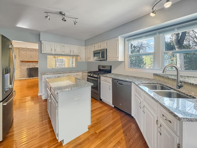 232 Southfield Dr, Vernon Hills, IL 60061 - kitchen with appliances with stainless steel finishes, a sink, track lighting, a kitchen island, and light wood-style flooring